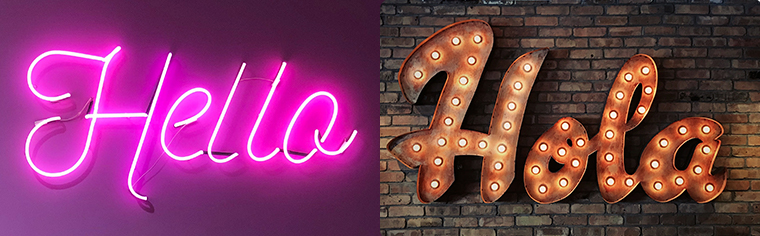 Neon sign that reads "Hello" glows pink. Alongside it is a lit sign that says "Hola."